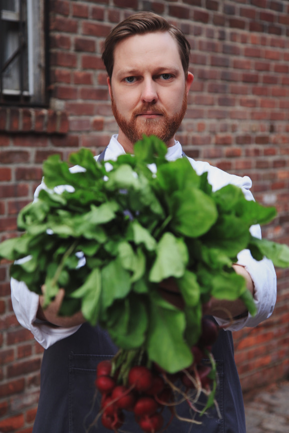 Chef Jeffrey holds radishes out in front of him